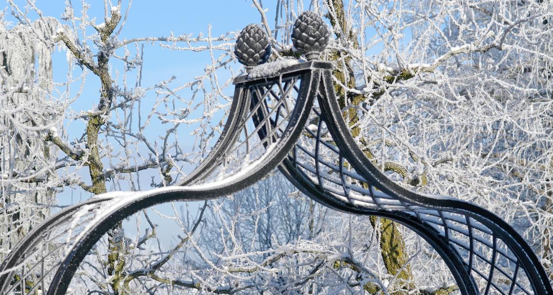 Metall Rosenbogen schwarz im Winter mit zwei Pinienzapfen