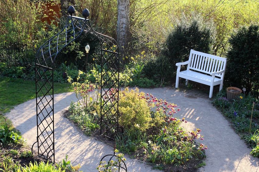 Rosenbogen Metall mit weißer Holzbank im Garten