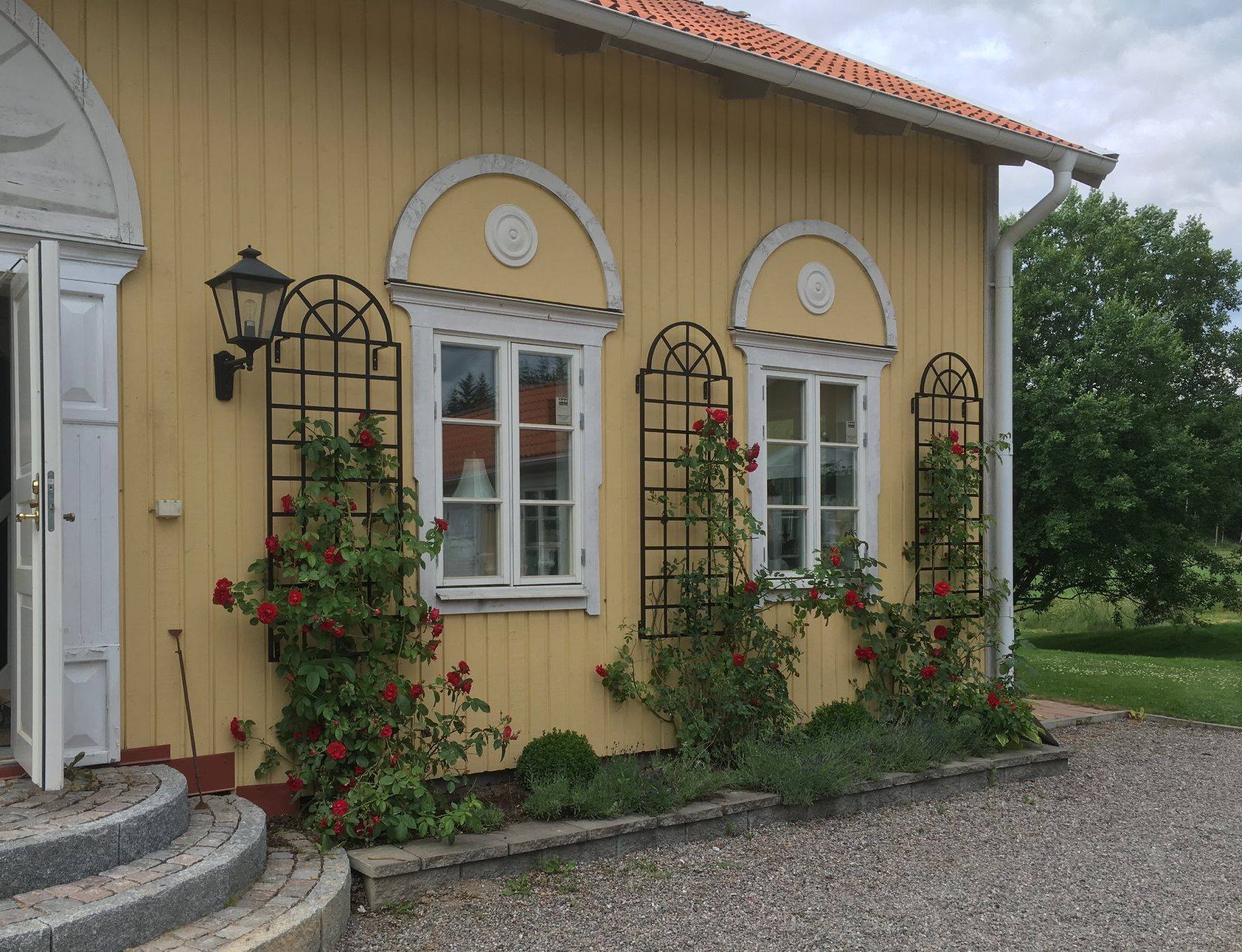 Drei Orangerie-Spaliere in Schwarz an gelber Hauswand in Schweden