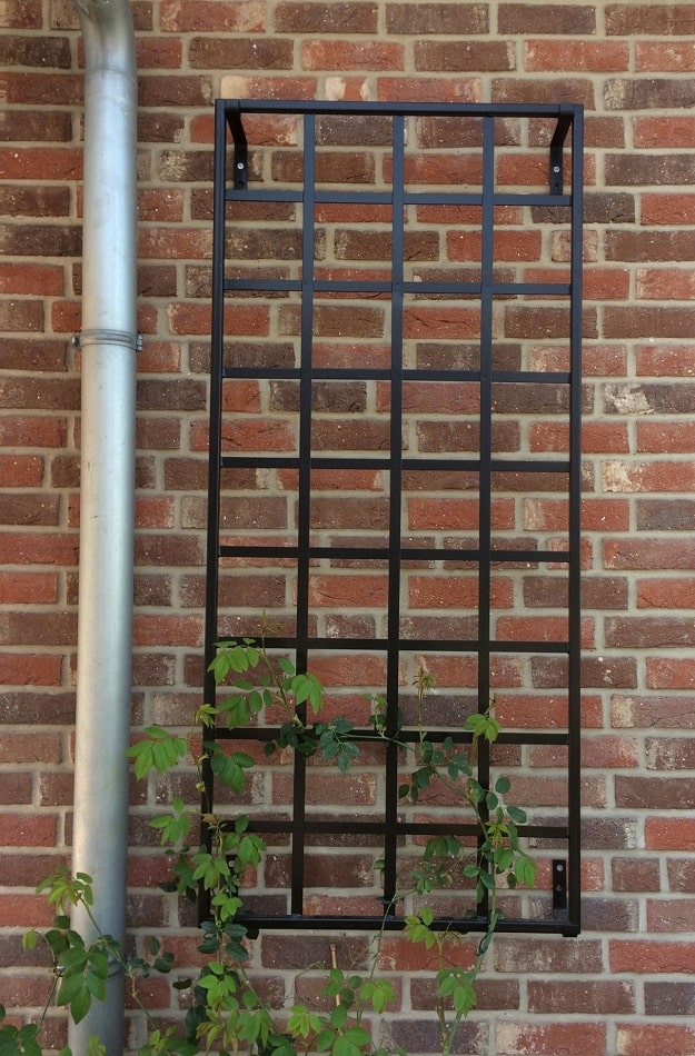 Kleines Rankgitter Bauhaus aus Stahl von Classic Garden Elements mit Rambler Rose an der Klinkerwand neben dem Fallrohr