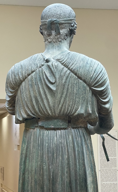 Wagenlenker von Delphi mit Stirnband des Champions und breitem Gürtel der Tunika Wagenlenker von Delphi mit Stirnband des Champions und breitem Gürtel der Tunika